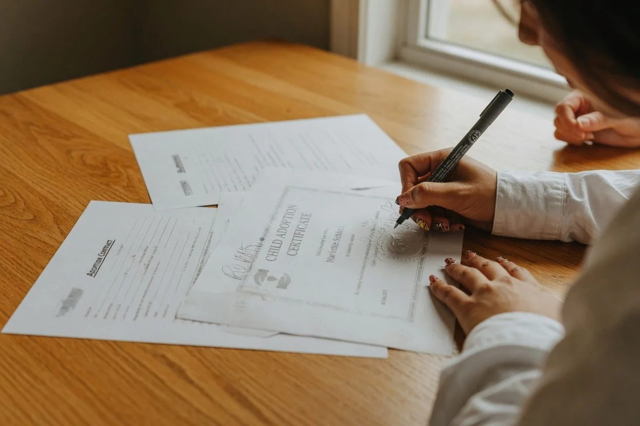 Hands signing a sworn document at a desk with a pen, illustrating notarizing a document for a family member in Ontario