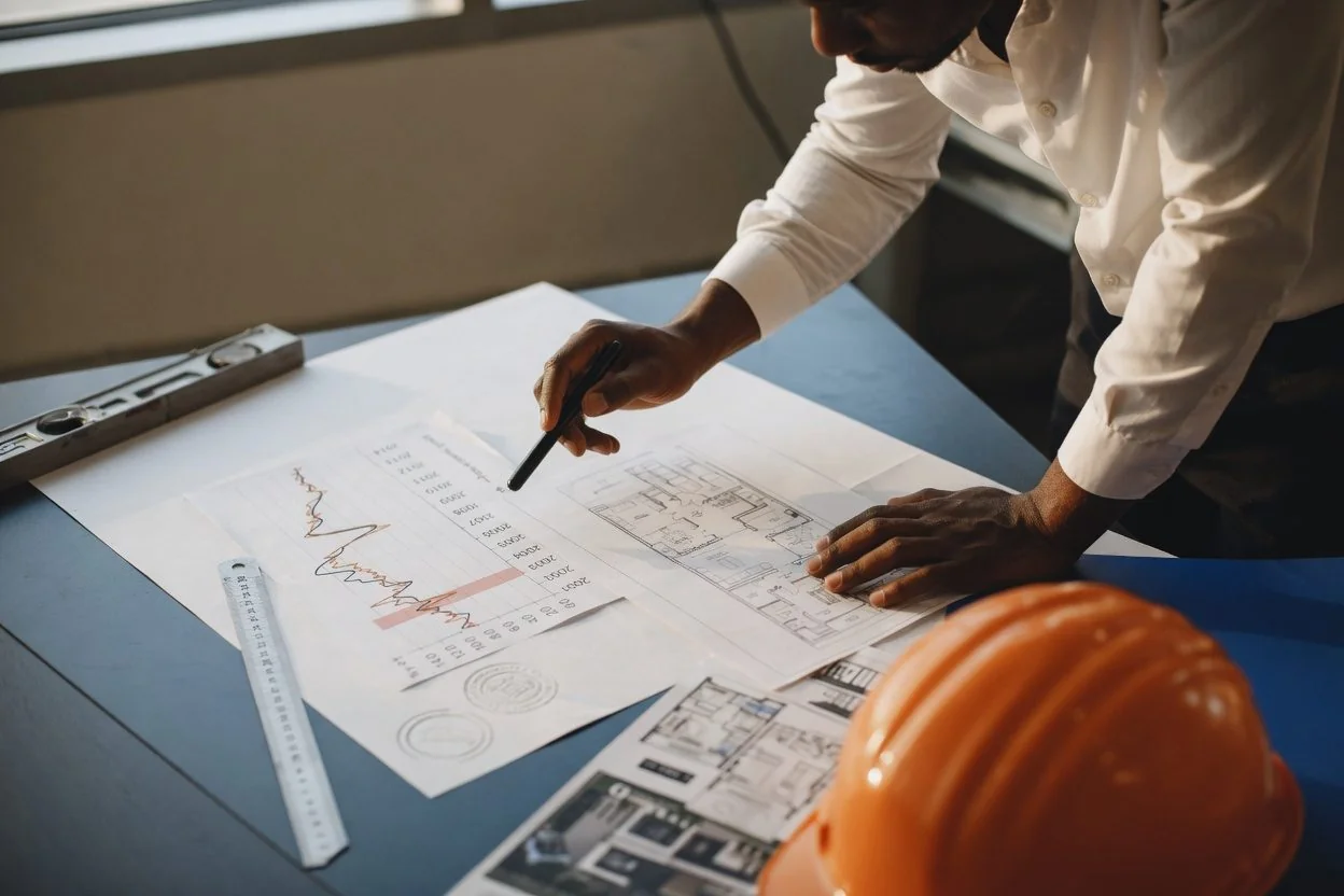 A close-up of an engineering blueprint with a pen and pencil resting on a desk