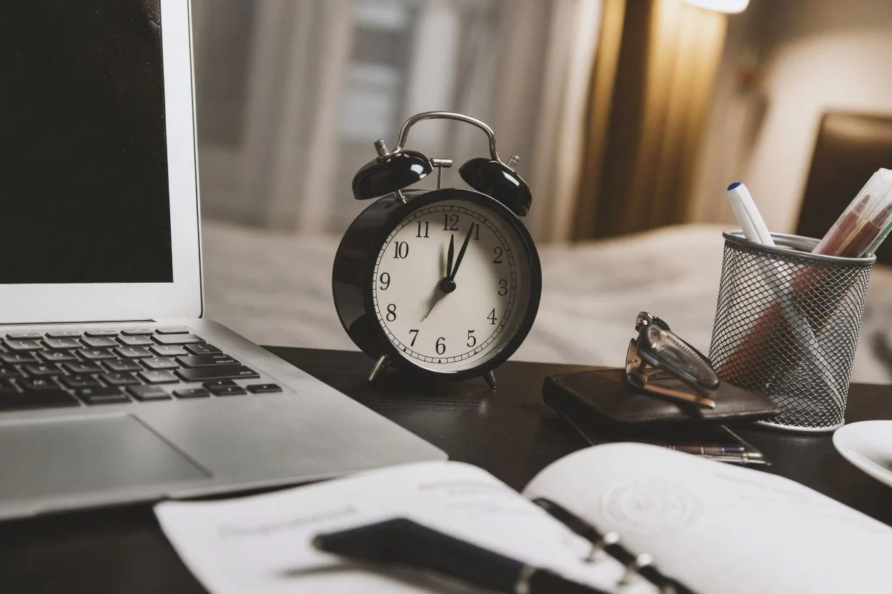 A tidy notary office desk with a wall clock and a small stack of documents